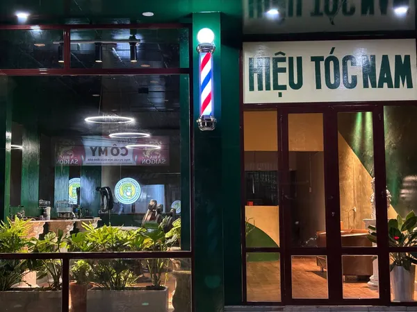 Storefront exterior with barbershop pole at night